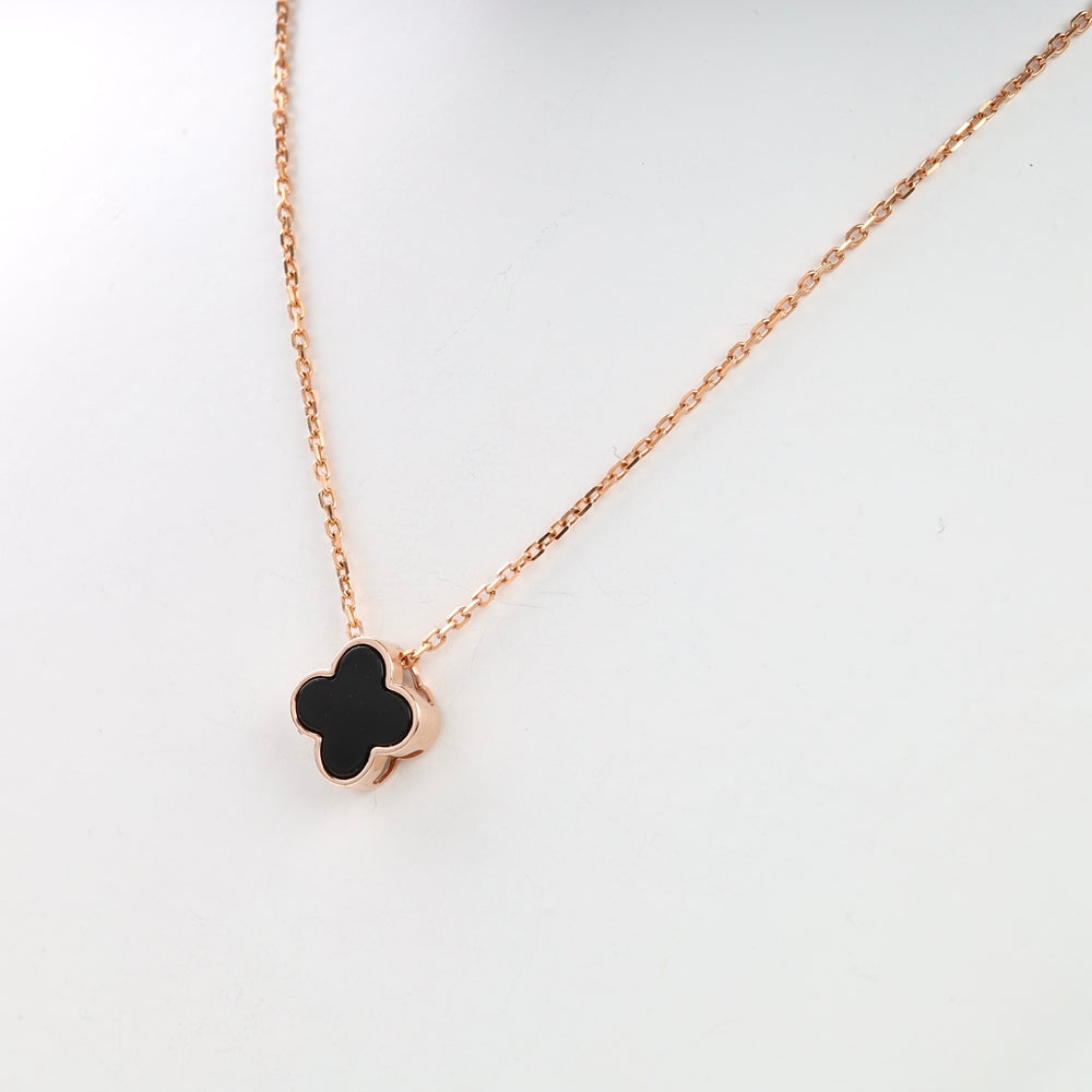 Rose gold necklace with black clover pendant on a chain.