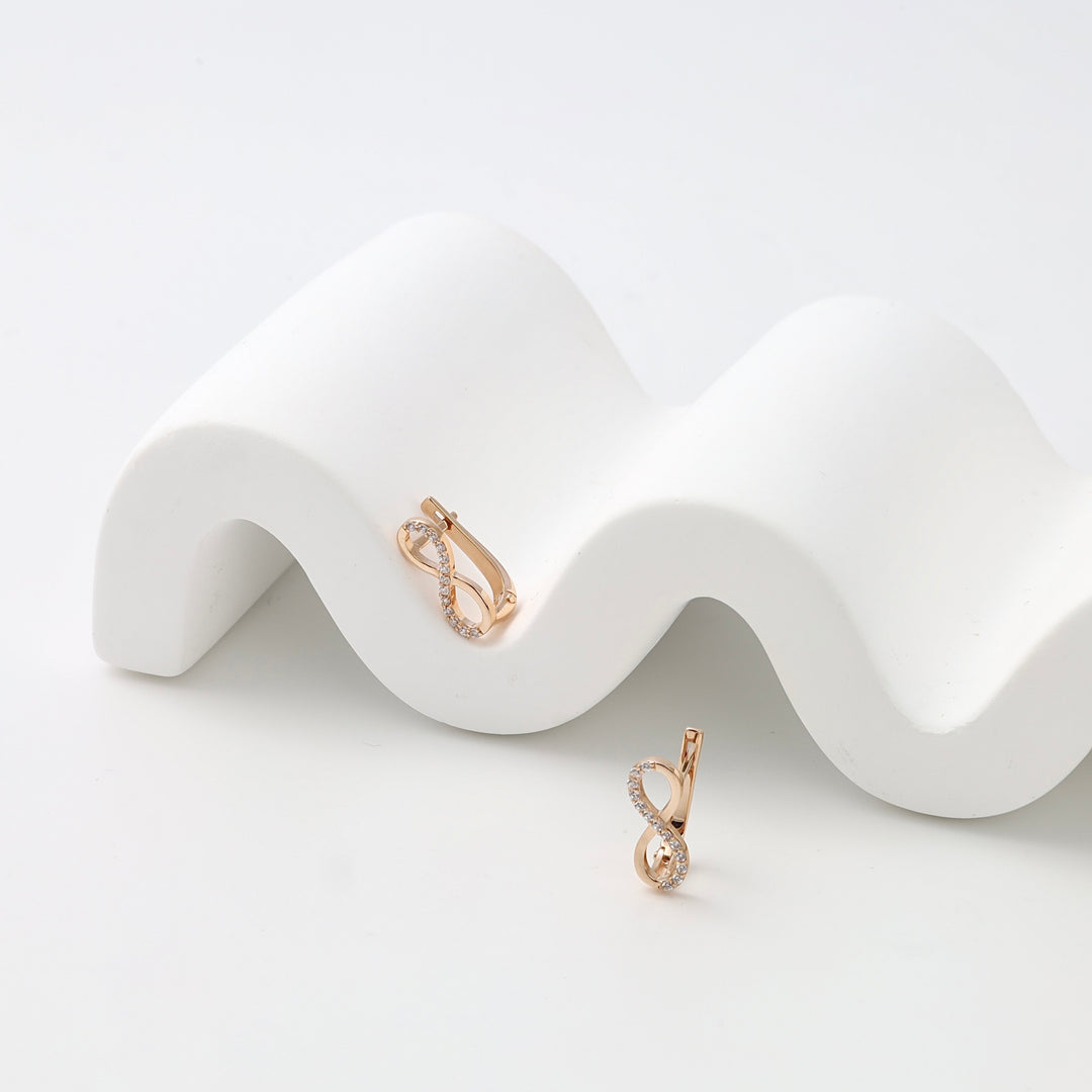 14k gold infinity hoop earrings with cubic zirconia, displayed on white stand, Ukrainian Jewelry, dainty gold earrings for women.
