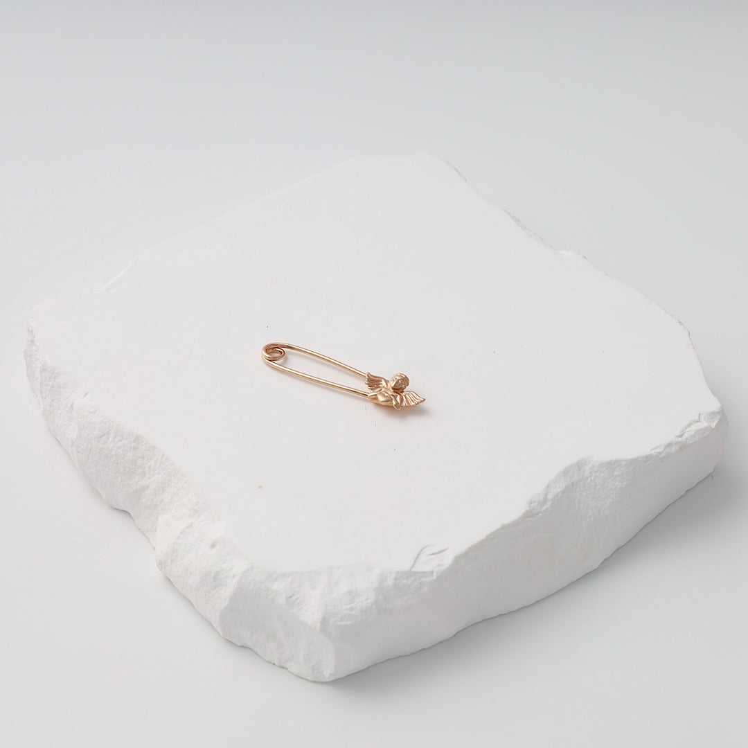 Gold safety pin brooch with small angel charm on white stone display, Ukrainian Jewelry, minimalist gold pin brooch gift.