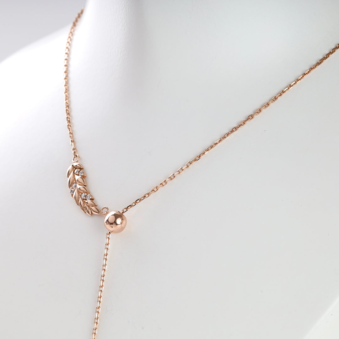 Rose gold necklace with a leaf motif and clear crystals, shown on a white bust. Necklace, leaf, rose gold, crystals.