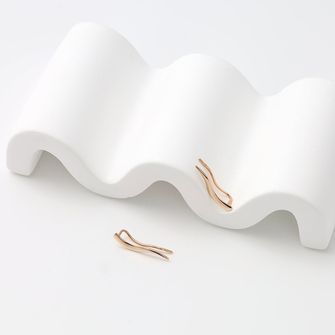 Single pair of 14k gold wave climber earrings displayed on white stand, minimalist ear crawler Ukrainian Jewelry for women.