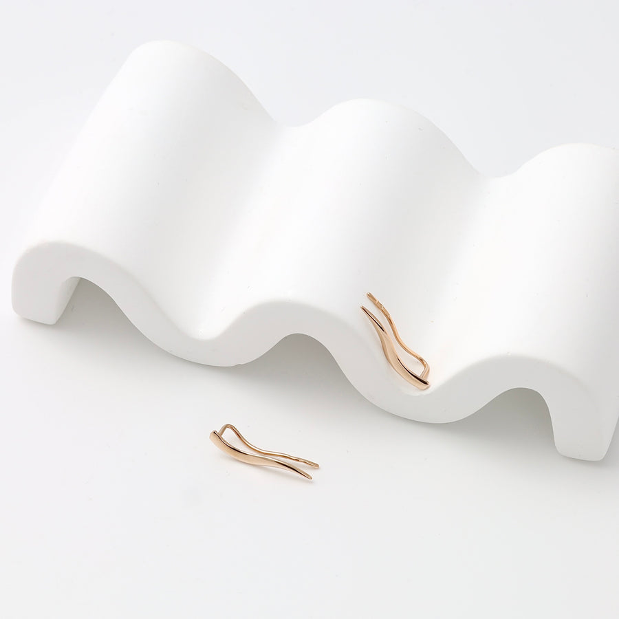 Single pair of 14k gold wave climber earrings displayed on white stand, minimalist ear crawler Ukrainian Jewelry for women.