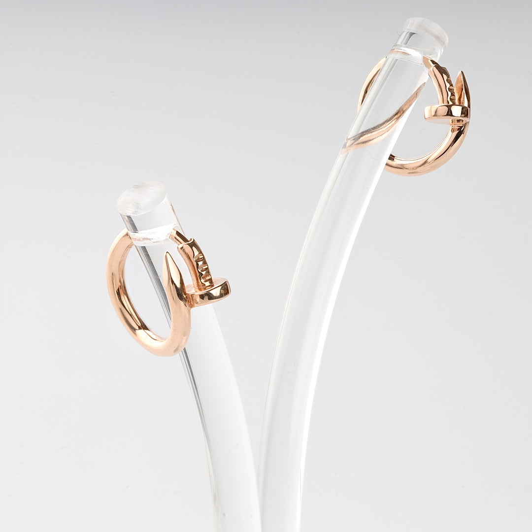 Pair of rose gold hoop earrings with nailhead motif displayed on clear curved rods, modern minimalist jewelry.