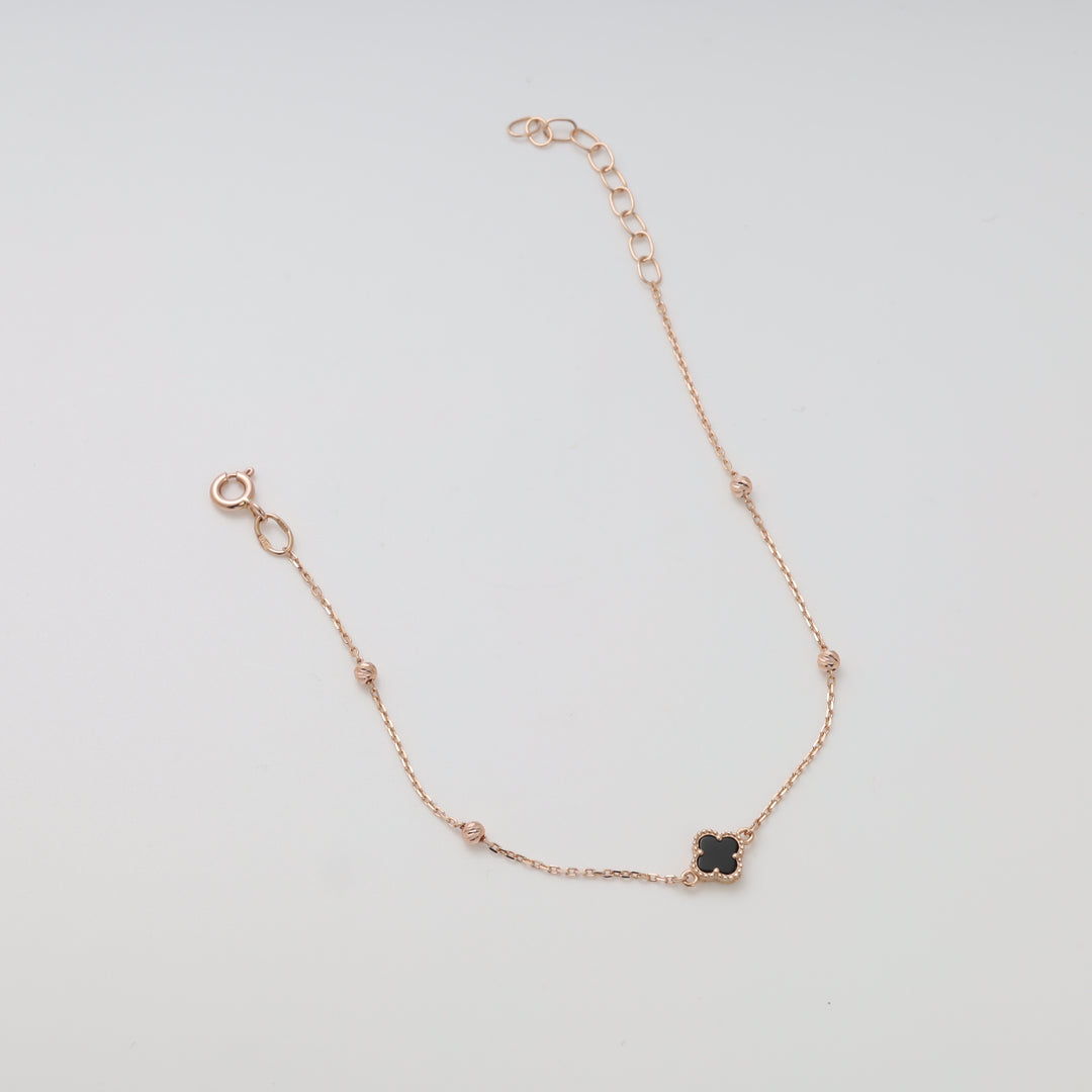 Delicate 14k gold chain bracelet with black clover charm and beads on white background, Ukrainian Jewelry, minimalist gold bracelet.