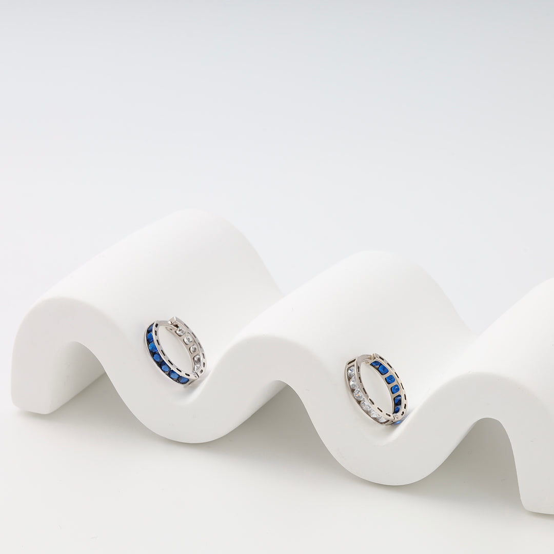 Sterling silver hoop earrings with blue and clear stones on white display, Ukrainian Jewelry, silver hoop earrings, sapphire huggies.