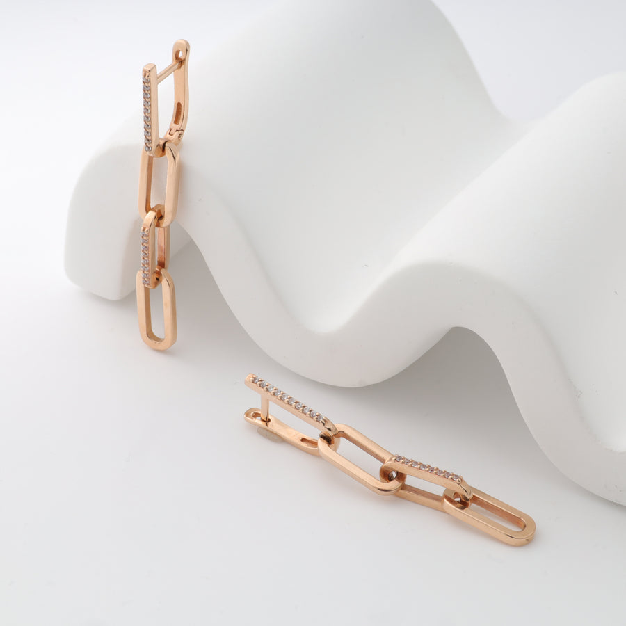 Rose gold chain link earrings with rhinestones on white background.