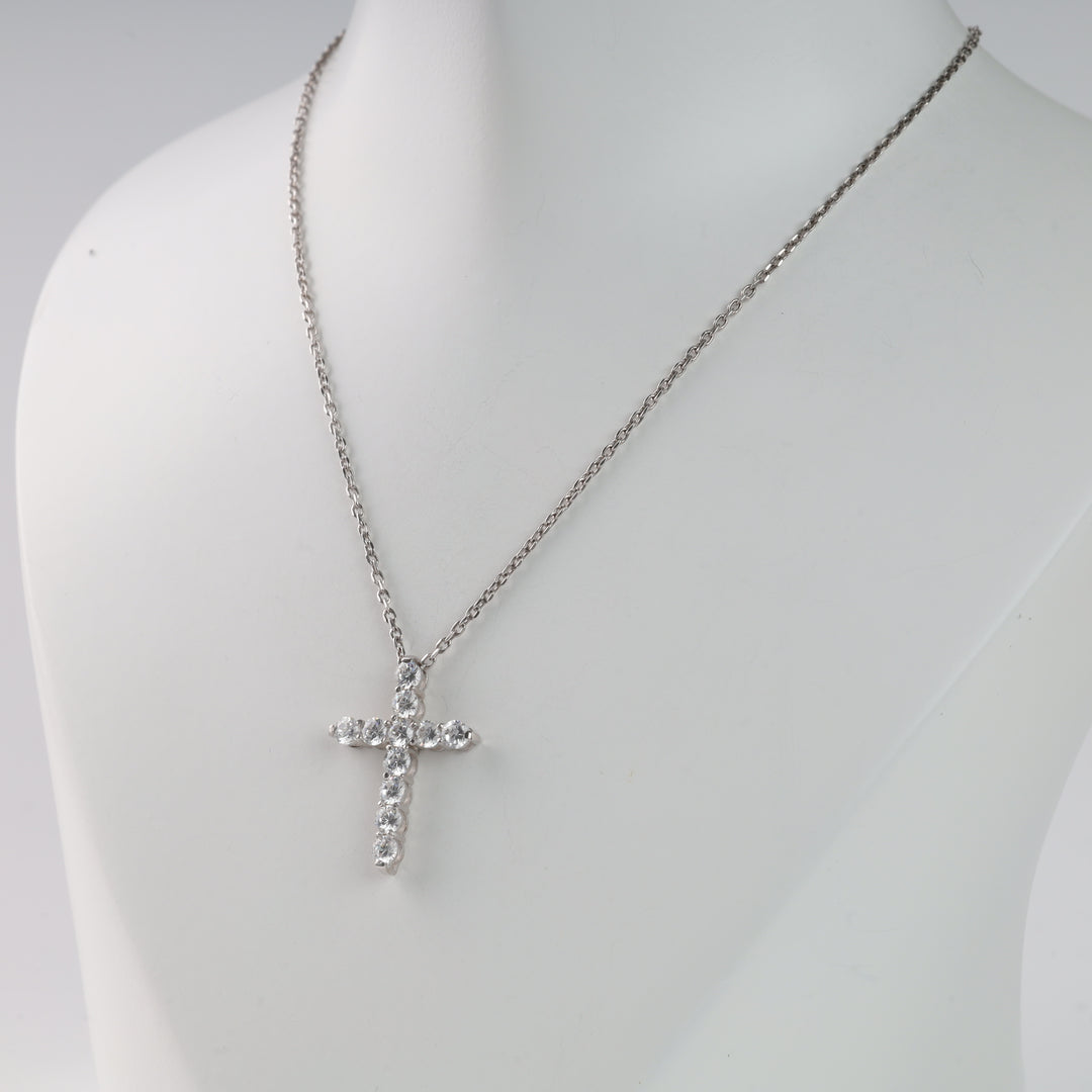 Silver chain necklace with a crystal-embellished cross pendant displayed on a white mannequin.