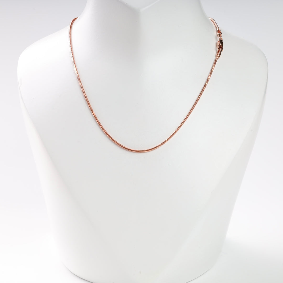 Rose gold snake chain necklace displayed on a white stand.