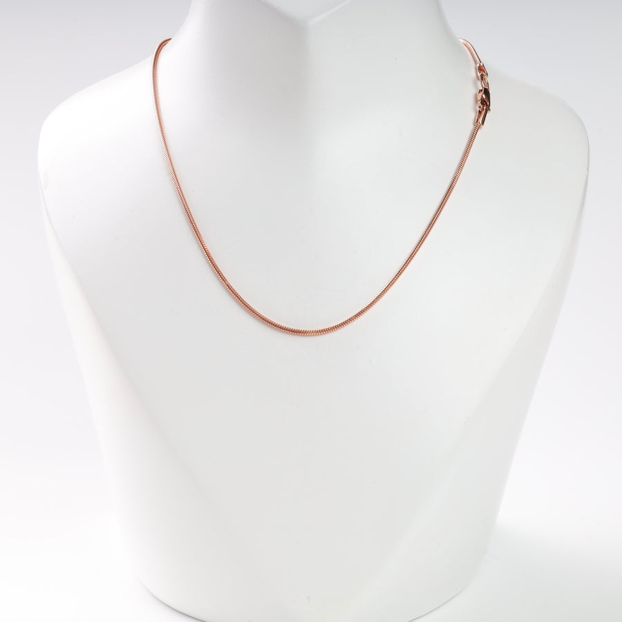 Rose gold snake chain necklace displayed on a white stand.