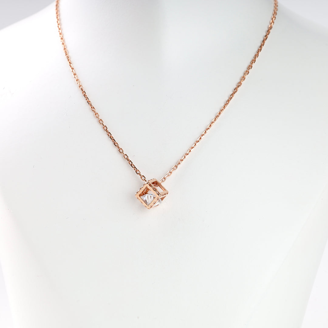 Rose gold chain necklace with a geometric square pendant and clear stone, displayed on a white bust.