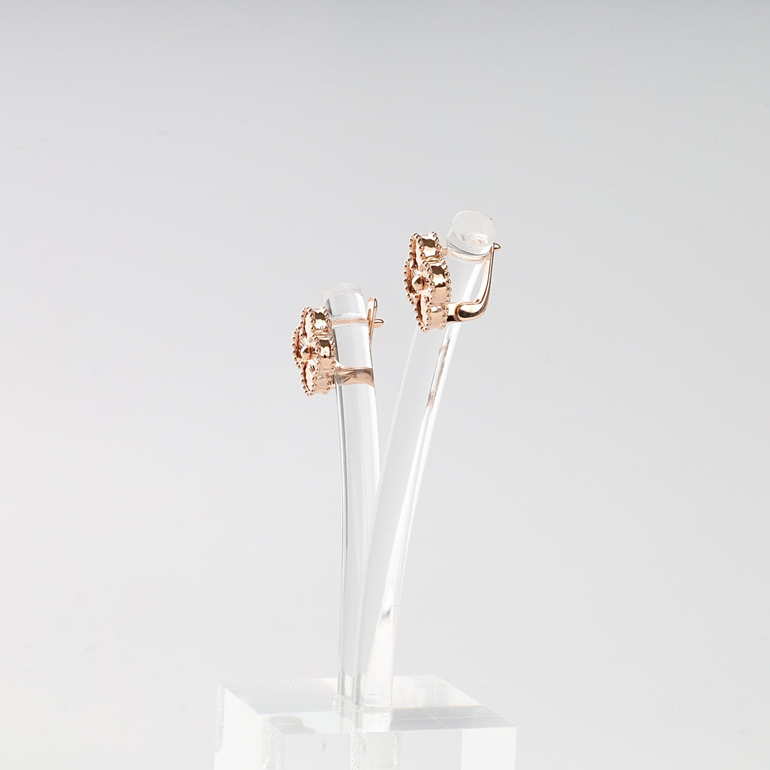 Pair of rose gold earrings on a clear stand against a light gray background