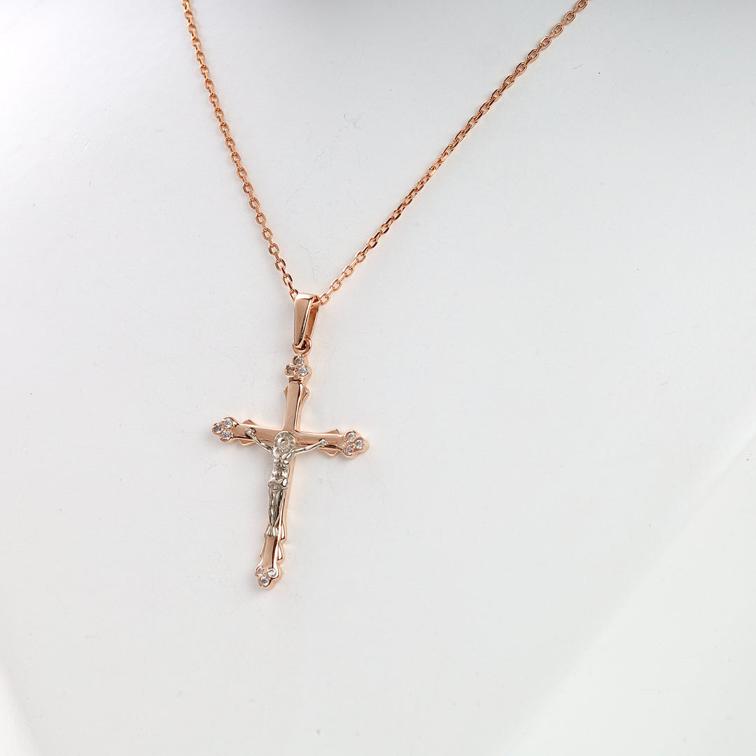 Rose gold chain necklace with a crucifix cross pendant featuring small clear stones, displayed on a white bust.