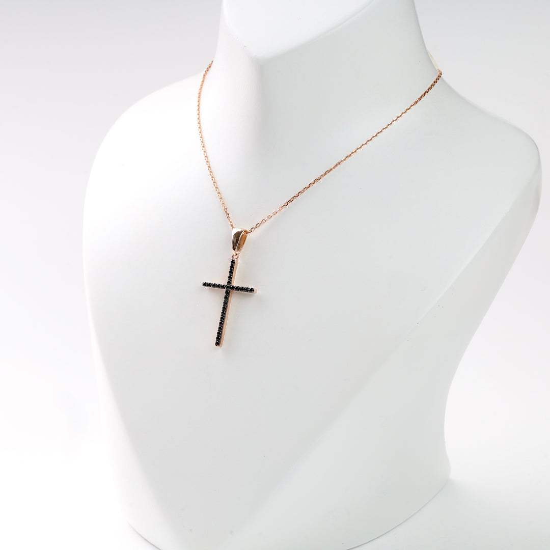 Gold chain necklace with black stone cross pendant displayed on a mannequin.