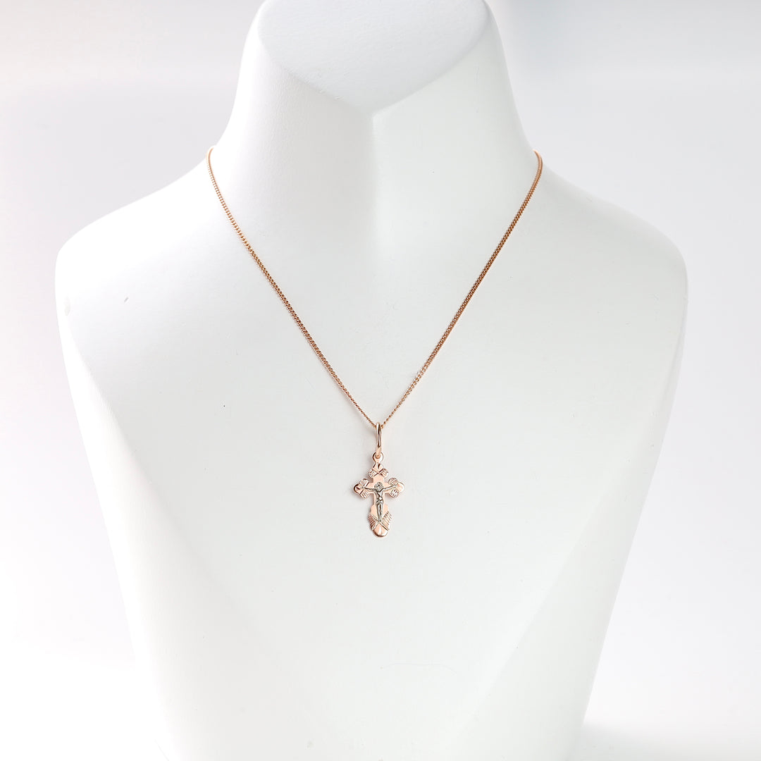 Gold cross pendant necklace with a crucifix motif displayed on a white jewelry bust.