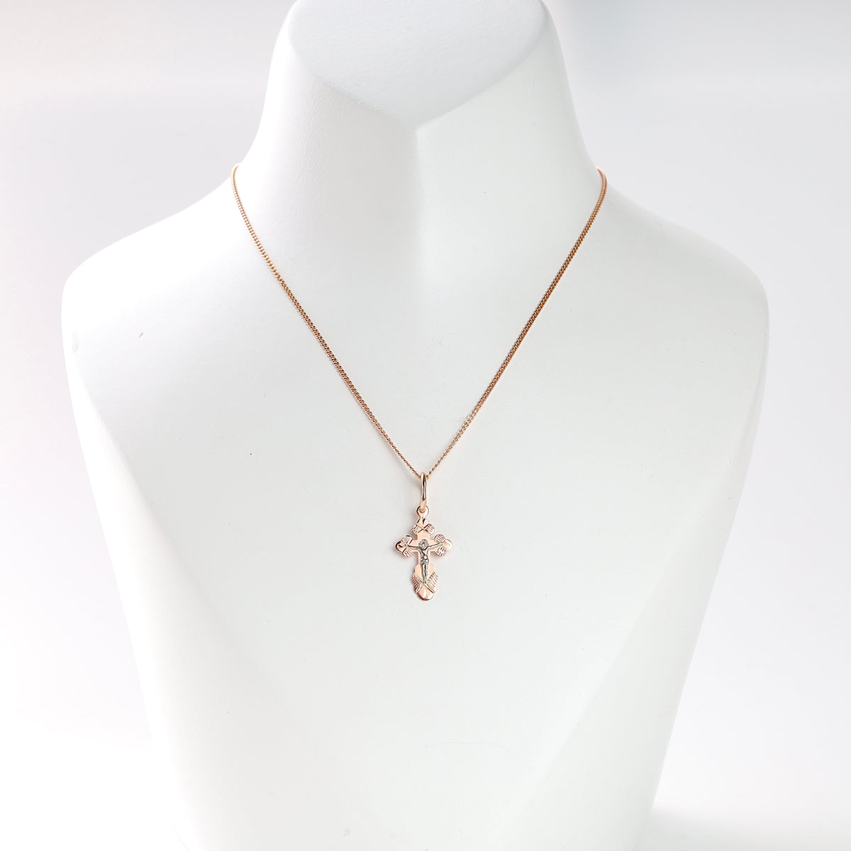 14K (585) rose gold crucifix pendant, shown on an illustrative chain on a white jewelry bust.