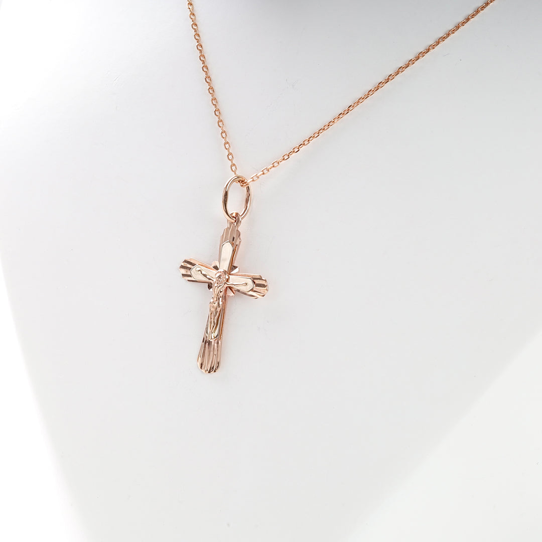 Rose gold crucifix pendant necklace with Jesus motif displayed on a white bust.
