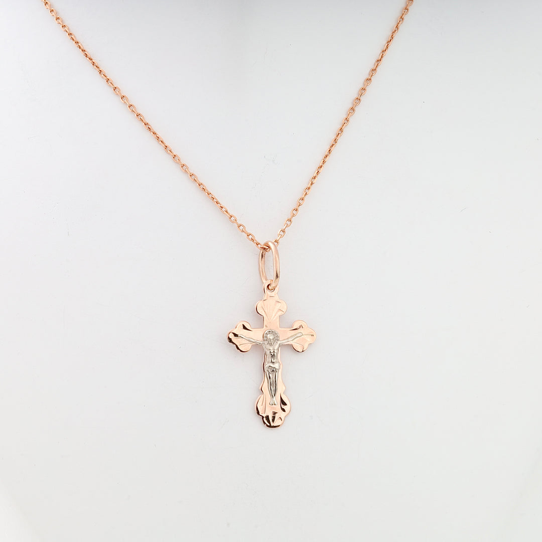 Rose gold cross pendant necklace with silver Jesus figure, displayed on a plain background.