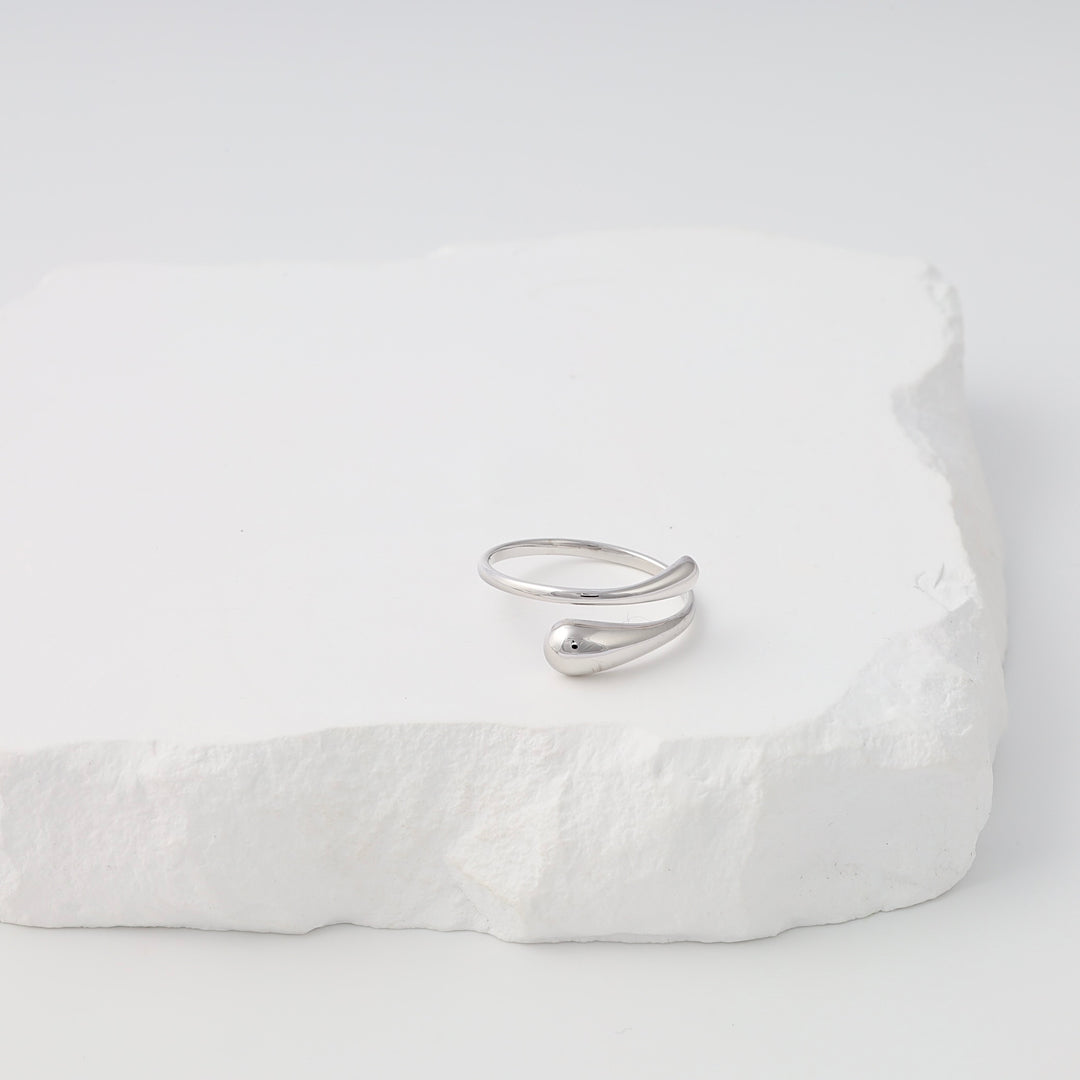 Sterling silver wrap ring with teardrop ends displayed on white stone, minimalist Ukrainian Jewelry, silver ring gift.
