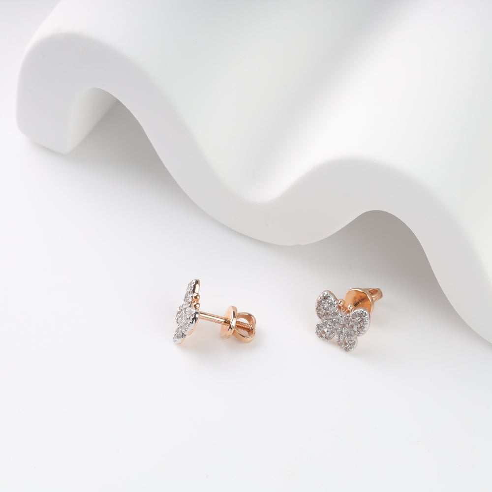 Rose gold diamond butterfly stud earrings on a white surface.
