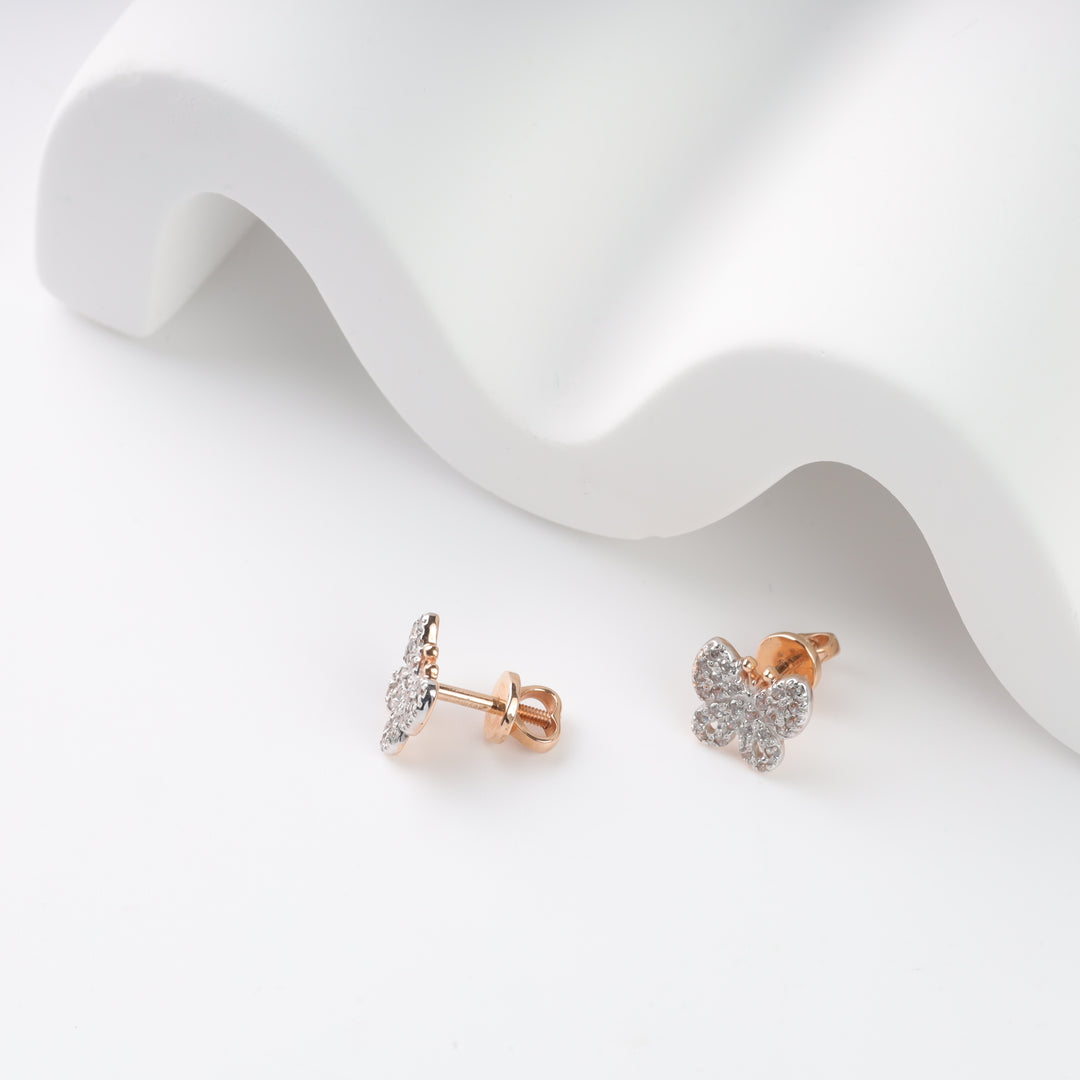 Rose gold diamond butterfly stud earrings on a white surface.