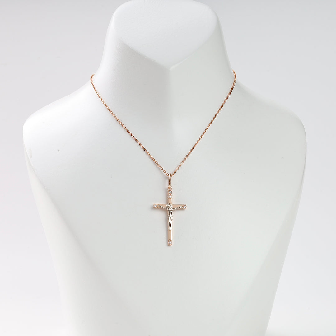 Gold chain necklace with a crucifix pendant featuring Jesus, displayed on a white jewelry bust.