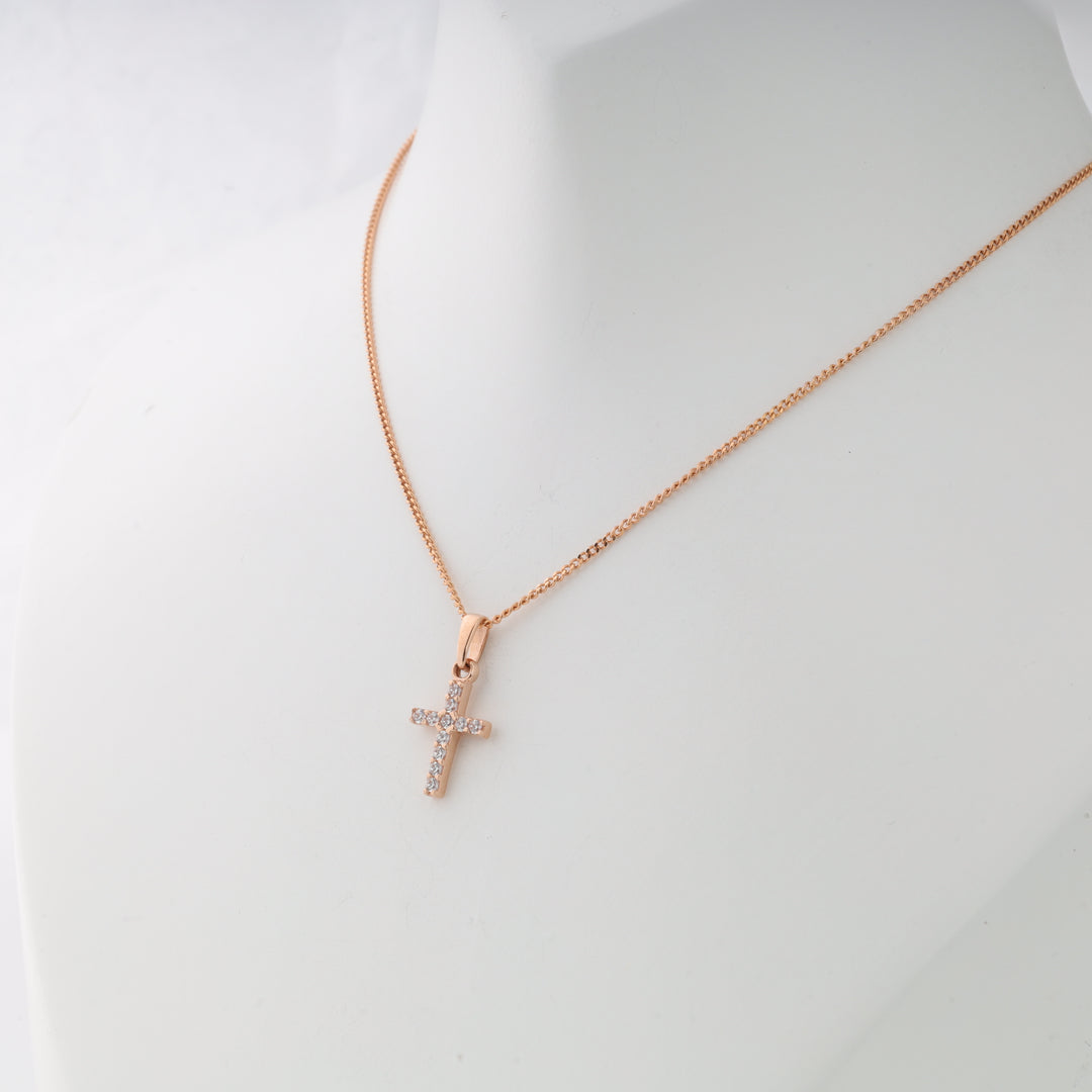 Rose gold chain necklace with a small cubic zirconia cross pendant displayed on a white bust.