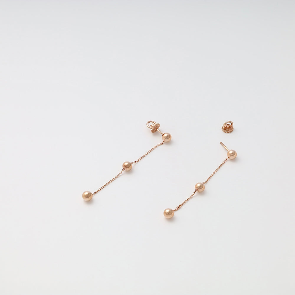 Pair of rose gold dangle earrings with three round beads on each, displayed on a plain white background.
