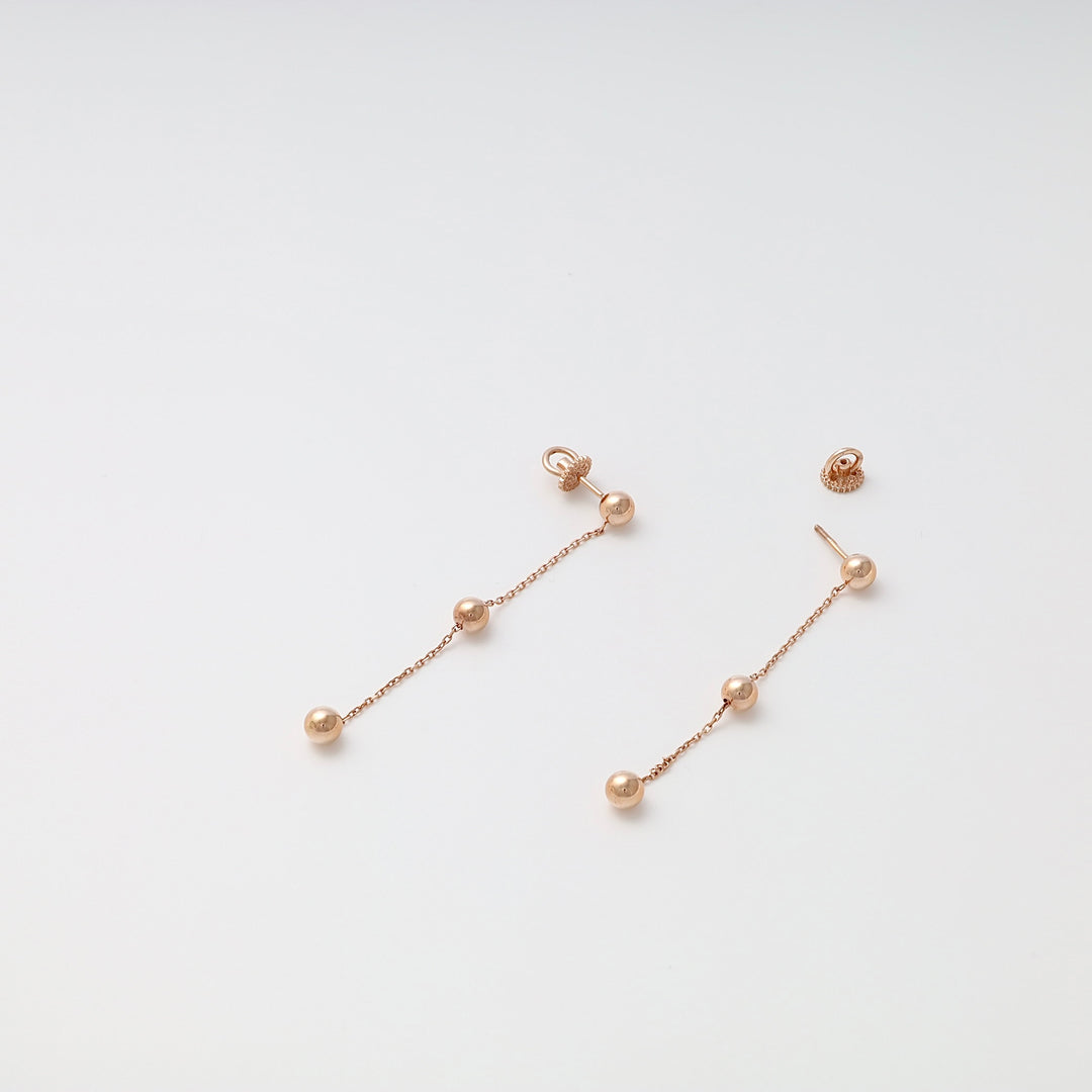 Pair of rose gold dangle earrings with three round beads on each, displayed on a plain white background.