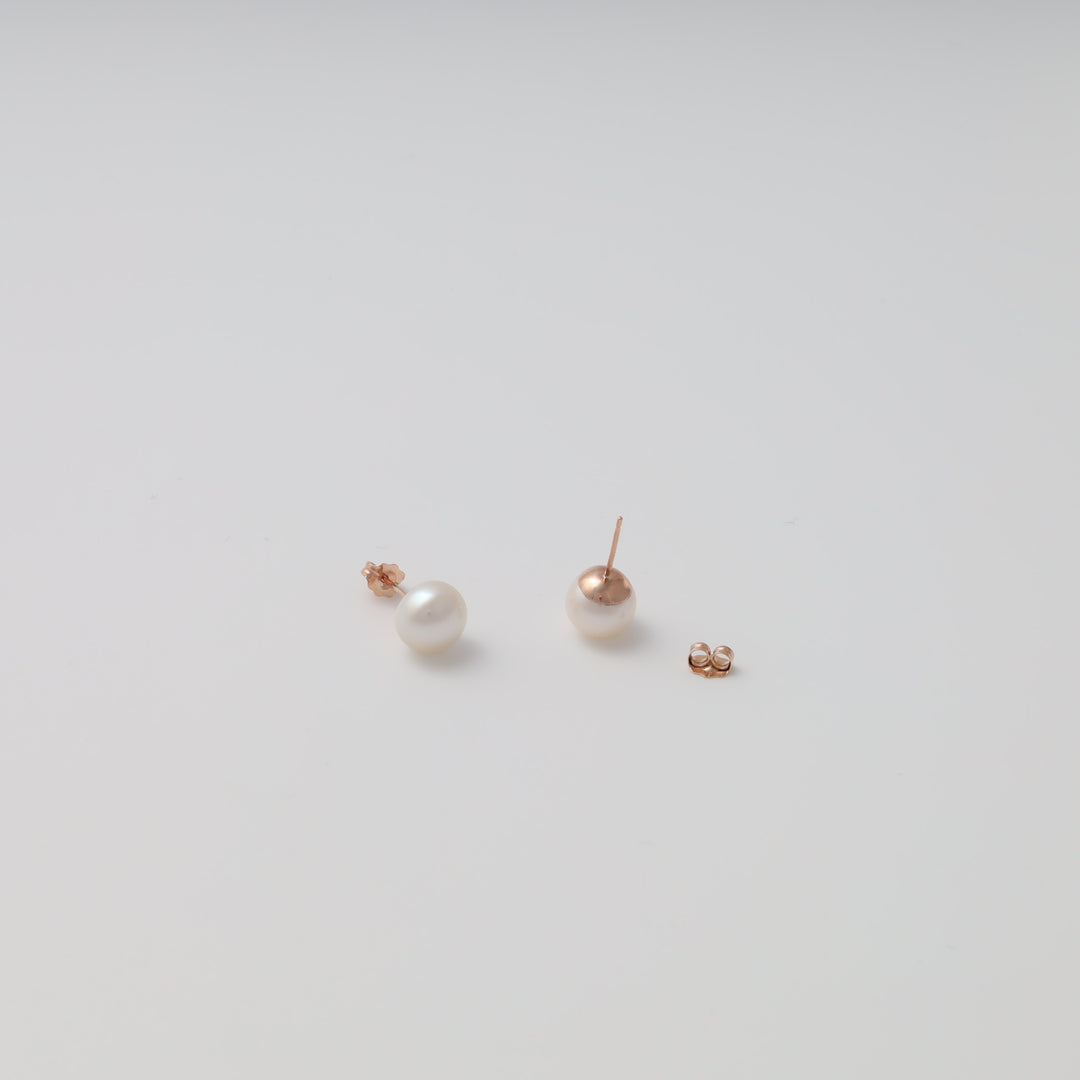 Single pair of 14k gold pearl stud earrings with butterfly backs on white background, Ukrainian Jewelry, minimalist pearl earrings.