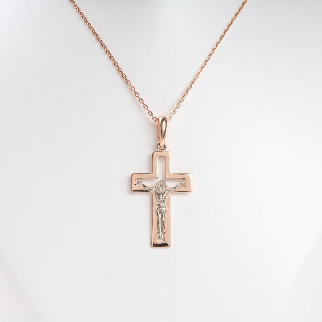 Rose gold crucifix pendant necklace with Jesus motif on a fine chain, displayed against a white background.