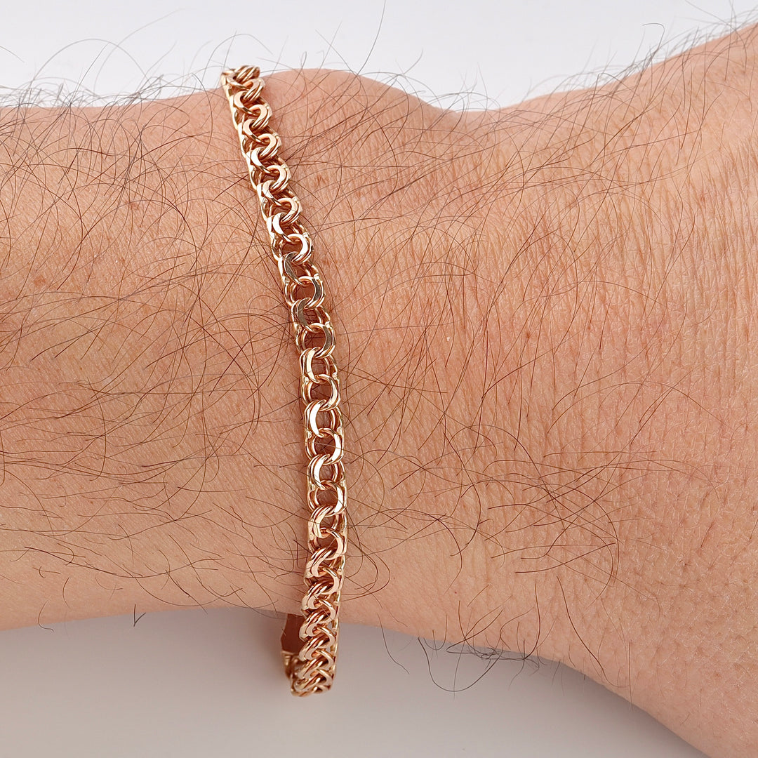 Gold chain link bracelet with a woven pattern shown on a wrist, jewelry, rose gold, chain bracelet.
