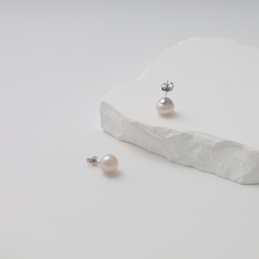 Sterling silver pearl stud earrings on white stone display, classic Ukrainian Jewelry, simple pearl earrings for women.