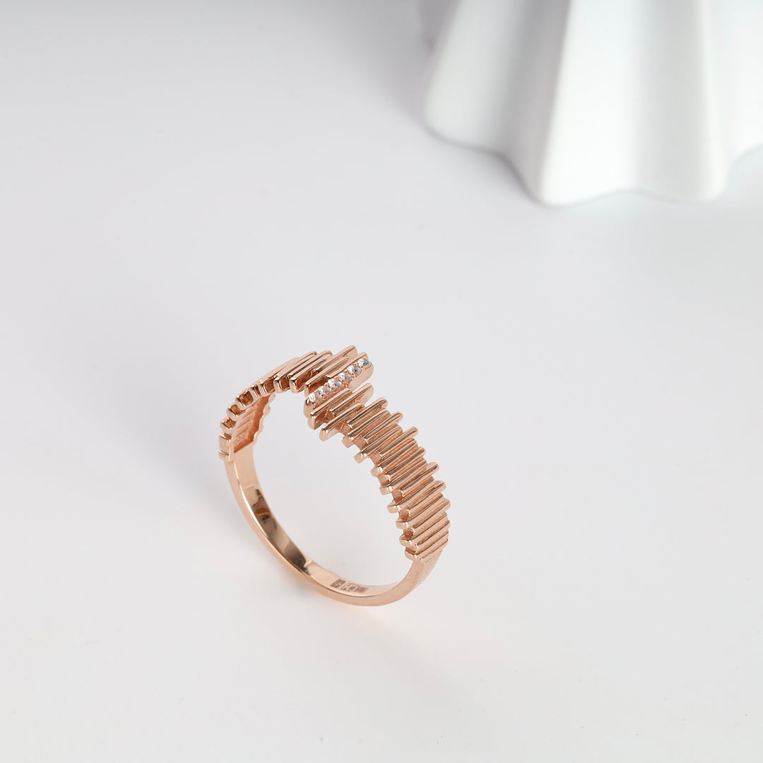 Rose gold ring with a textured bar design and small clear stones on a white background, minimalist stacking ring.