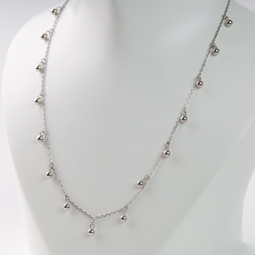 Silver chain necklace with small round beads, displayed on a white bust.
