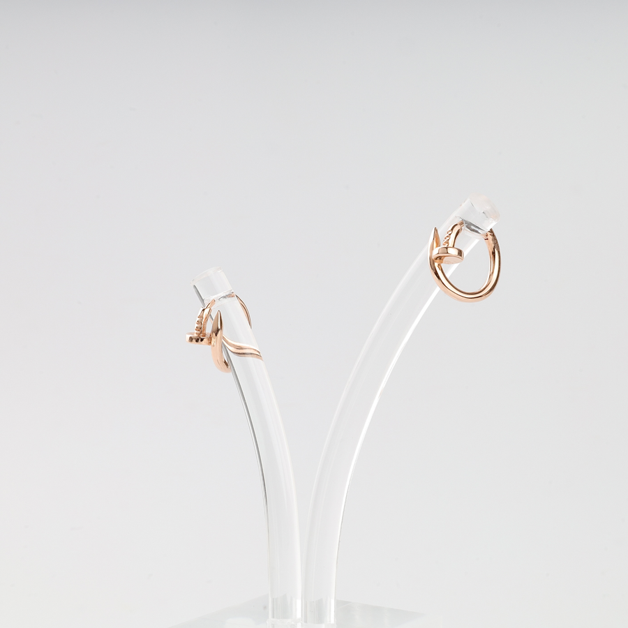 Pair of rose gold hoop earrings with minimalist curved shapes displayed on clear acrylic stands.