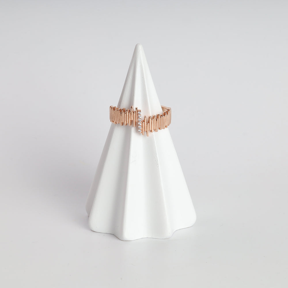 Rose gold bar pattern ring with small clear crystals displayed on a white ceramic cone.