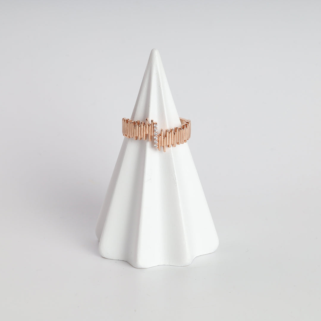 Rose gold bar pattern ring with small clear crystals displayed on a white ceramic cone.
