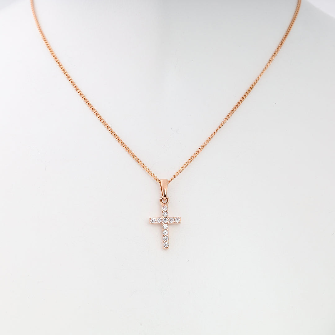 Rose gold chain necklace with a small crystal cross pendant displayed on a white bust, dainty cross jewelry.