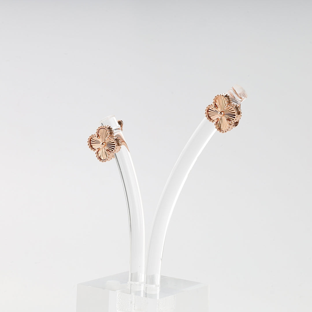 Pair of gold and clear earrings on a light gray background