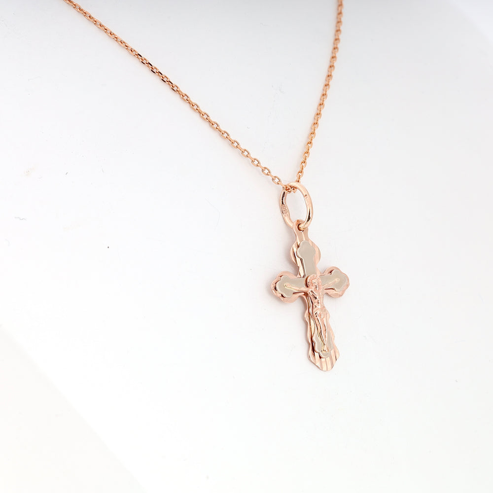 Rose gold chain necklace with a crucifix cross pendant featuring an embossed figure, shown against a white background.