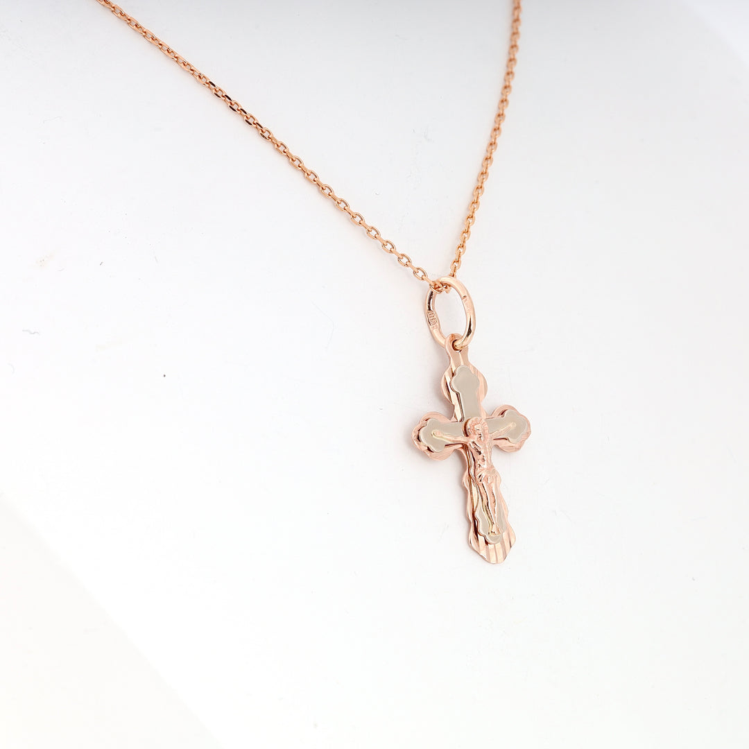 Rose gold chain necklace with a crucifix cross pendant featuring an embossed figure, shown against a white background.