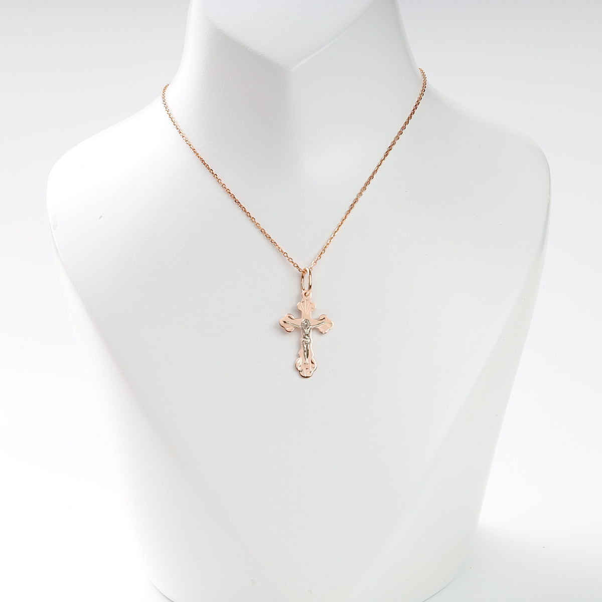 Gold chain necklace with a two-tone crucifix pendant displayed on a white jewelry bust for religious jewelry searches.