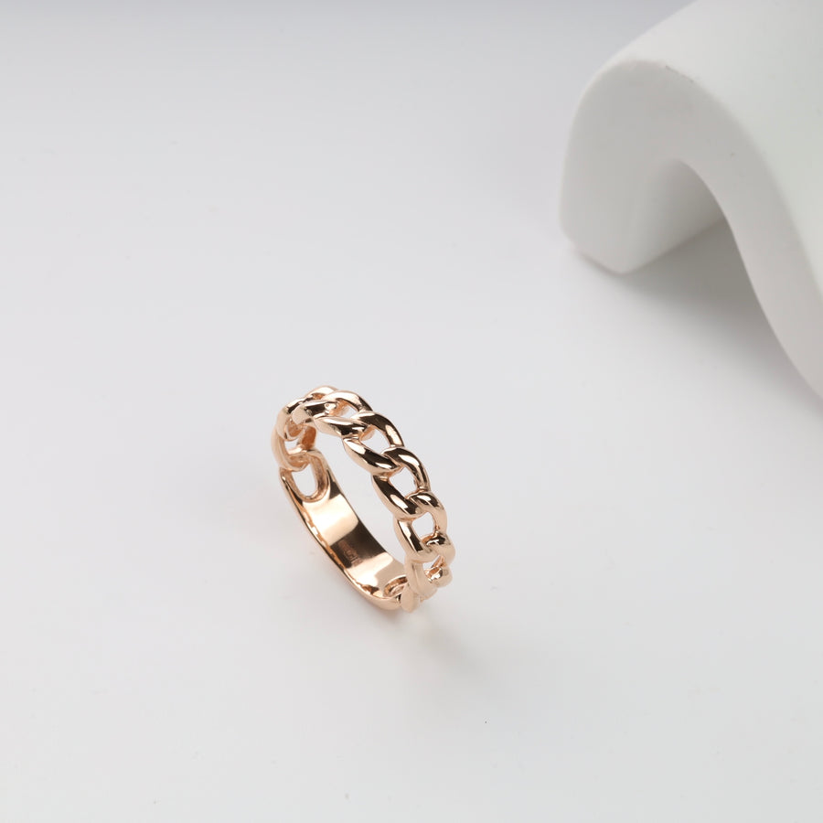 Gold chain link band ring on a white surface.