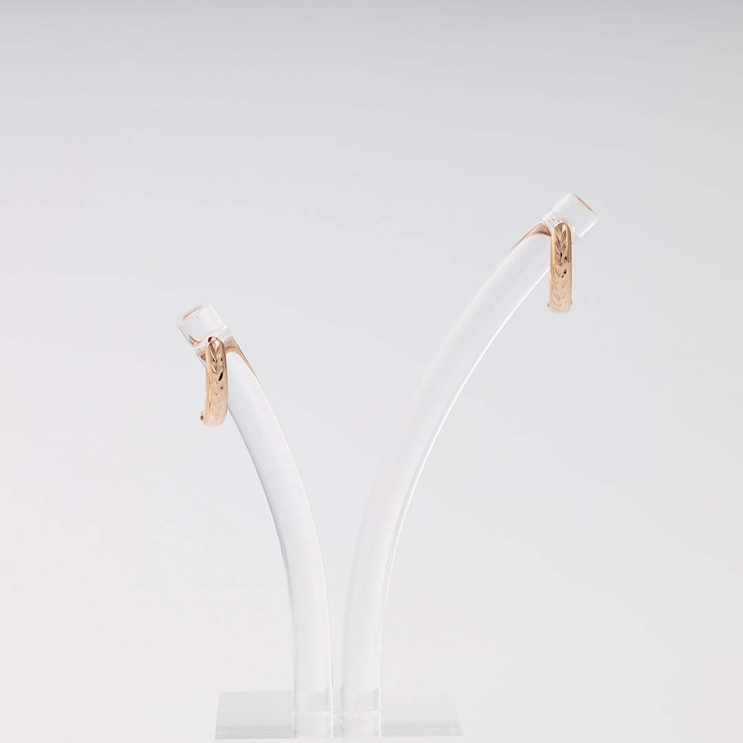 Pair of 14k gold engraved huggie hoop earrings on a display stand, Ukrainian Jewelry, minimalist gold earrings gift.