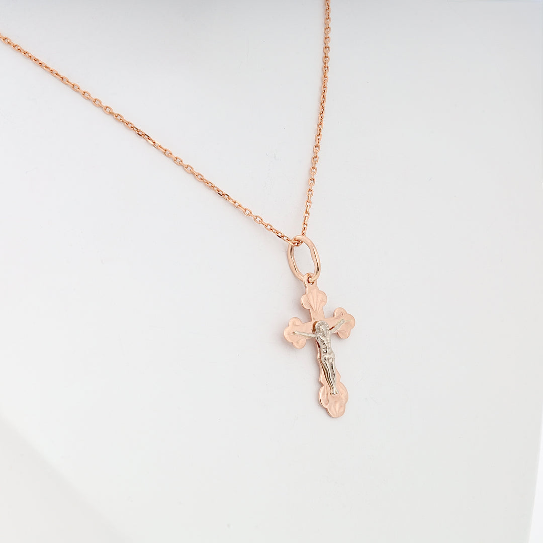 Rose gold chain necklace with a two-tone crucifix pendant displayed on a white background. Cross jewelry, Christian necklace.