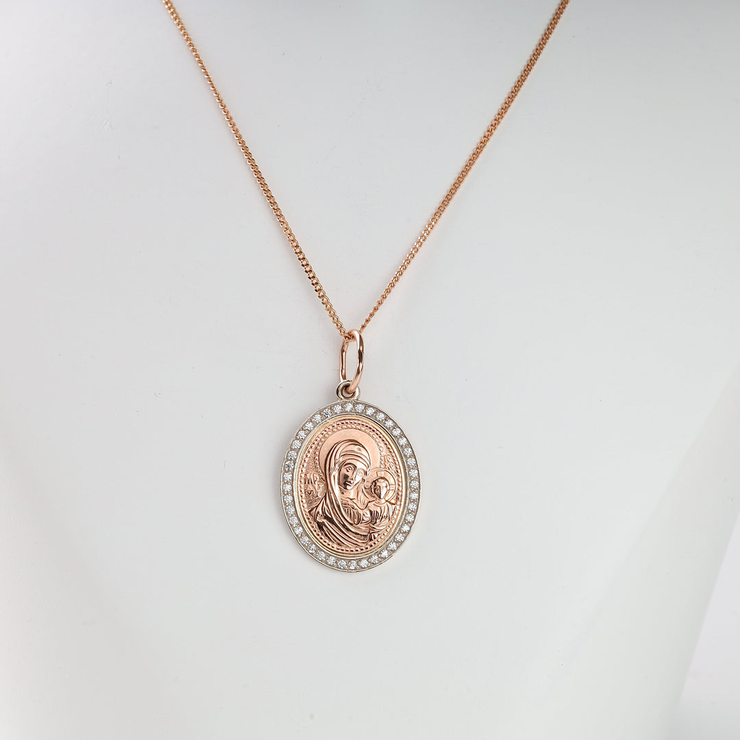 Rose gold oval pendant necklace featuring a Madonna and child motif with a halo of small clear stones, displayed on a white bust.