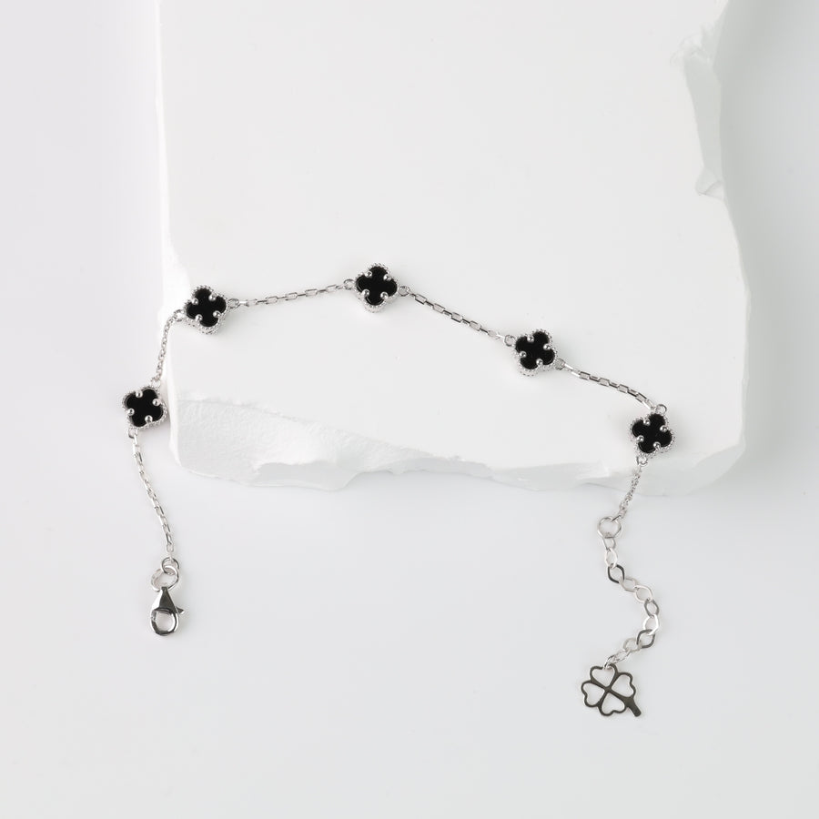 Silver chain bracelet with five black enamel four-leaf clover charms displayed on a white background.