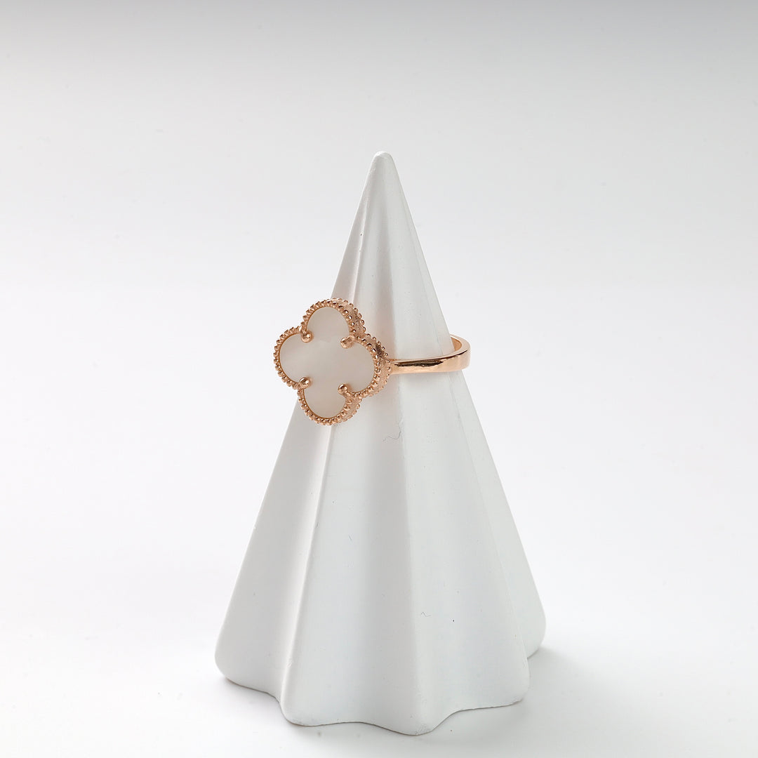 Gold ring with a white clover-shaped motif displayed on a white cone stand, floral ring, gold jewelry.