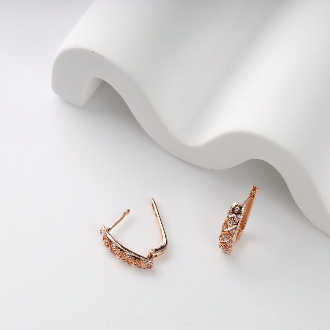 Rose gold earrings with diamond motifs on white surface.