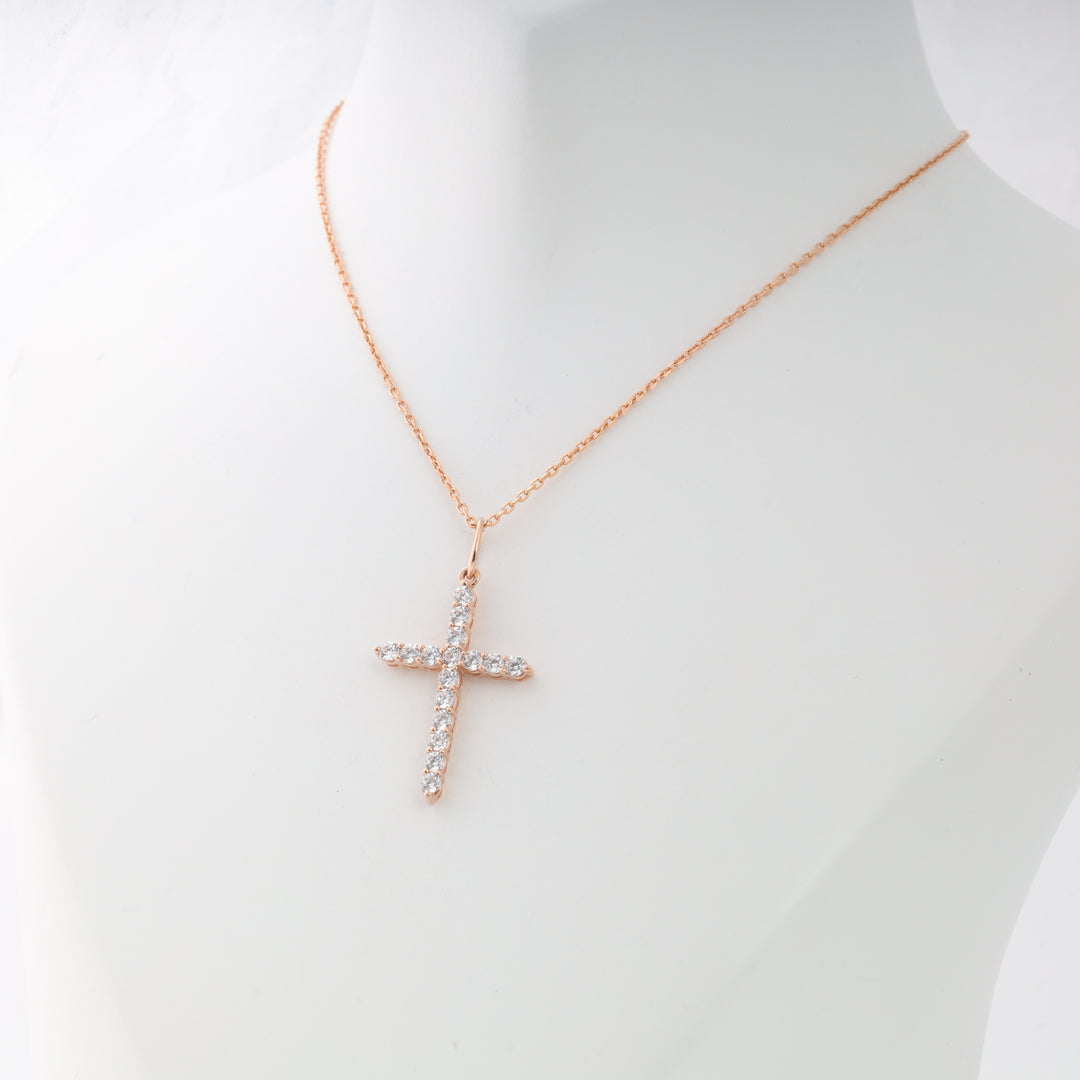 Gold chain necklace with a cross pendant made of clear rhinestones displayed on a white mannequin bust.